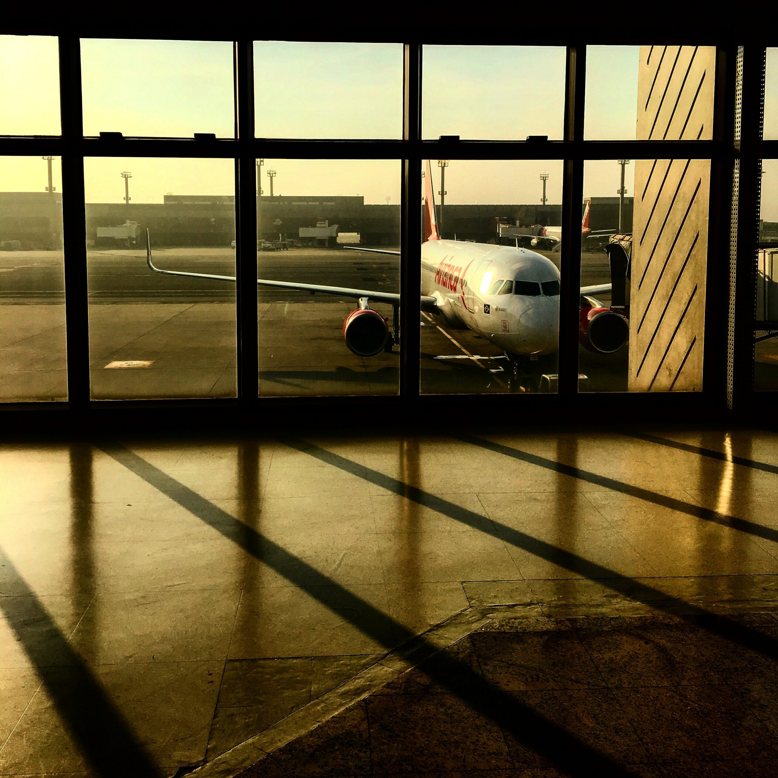 A white aeroplane seen through the windows of an airport.